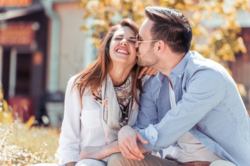 Happy young couple sitting on a bench together.