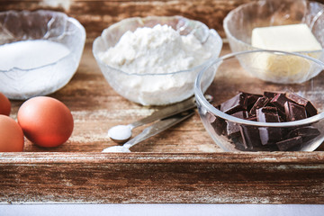 Baking ingredients for chocolate cake muffins or cookies lying ready on wooden kitchen tray. Mise en place, white background, measured ingredients.