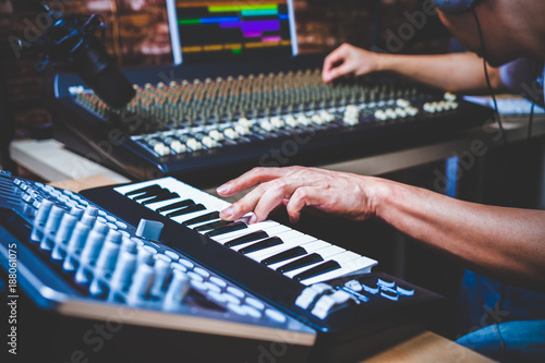 Fotografía male musician playing midi keyboard synthesizer in recording studio, focus on ha