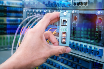 Wall Mural - man working in network server room with Fiber Optic cables connected to optic ports