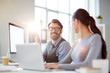 © pressmaster - Happy man talking to his female colleague during discussion of working tasks