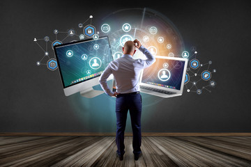 Businessman in front of a wall with computer and devices displayed on a futuristic interface with business network - Multimedia and technology concept