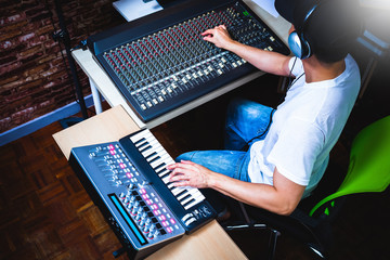 Wall Mural - male musician playing midi keyboard synthesizer in recording studio