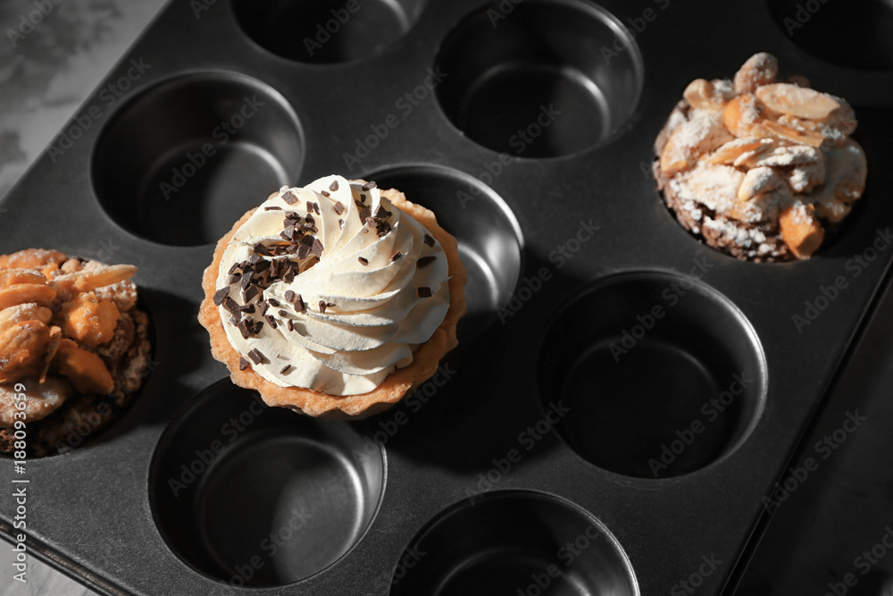 Muffin tin with tasty pastries, closeup