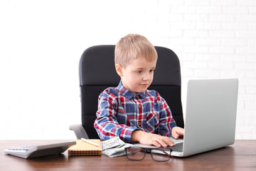 Poster - Cute little boy with laptop and money at table indoors