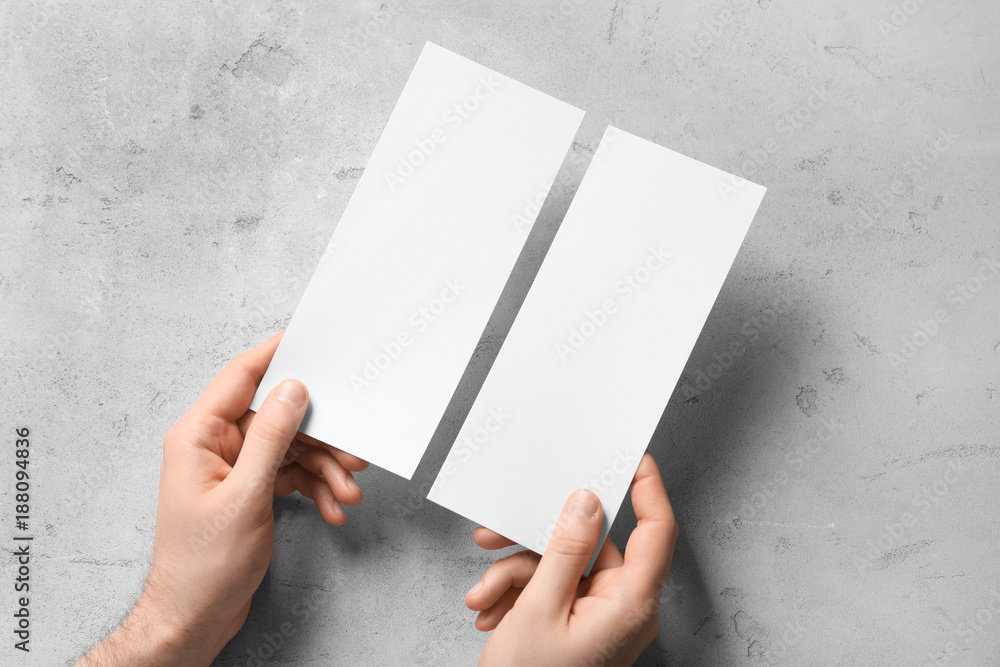 Man holding blank cards on grey background. Mock up for design
