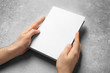 © Africa Studio - Man holding book with blank cover on grey background. Mock up for design