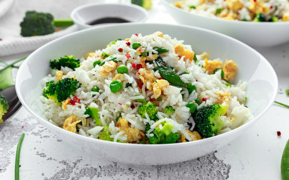 Fried rice with vegetables, broccoli, peas and eggs in a white bowl. healthy food