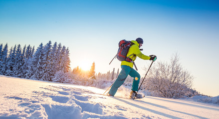 Sunny winter landscape with man on snowshoes.