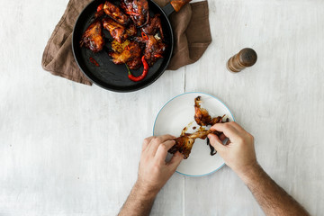 Poster - Man eats chicken wings, top view. Dinner table concept