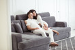© uv_group - Portrait of young couple sitting together on grey sofa in modern white apartment or domestic room. Happy lovely family embracing and hugging together close-up