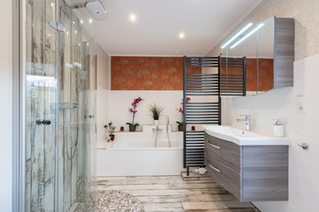 Modern bathroom in vintage style with sink, bathtub, glass shower and black towel dryer