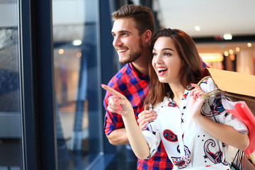 sale, consumerism and people concept - happy young couple with shopping bags walking in mall.