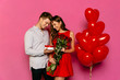 Handsome man and attractive woman looking at box with gift, red roses, balloons while celebrating a St. Valentine's day.