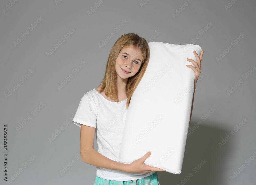 Cute girl with big pillow on grey background