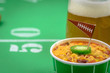closeup of a small bowl of chili and beer mug on table decorated for superbowl party