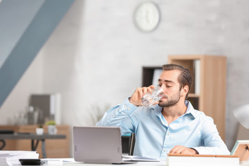 Young man drinking water in office