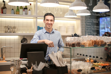 Canvas Print - Young man standing in store. Small business owner portrait