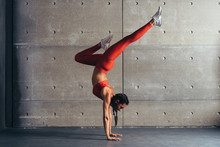 Young Fit Woman Doing Handstand Exercise In Studio.