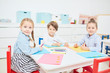 © pressmaster - Cute fritndly kids in casualwear gathered by table in kindergarten to draw
