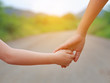 © zilvergolf - Close up of Sister hold hands with small children walking on the road.