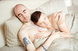 © pressmaster - Young homosexual lovers sleeping in bed under blanket in embrace