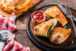Italian food, closed pizza calzone with Spinach and Cheese, wooden background, copy space