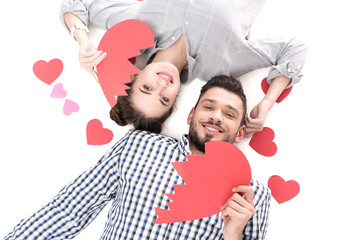 overhead view of couple lying with paper heart pieces isolated on white, valentines day concept