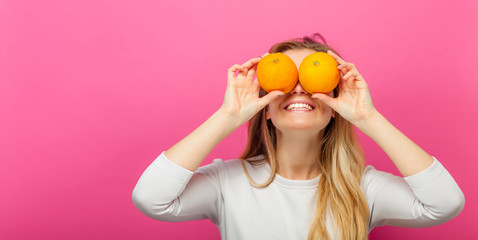 Girl with two orange fruits on pink background