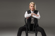 © LIGHTFIELD STUDIOS - portrait of young stylish woman sitting on chair and looking at camera isolated on grey
