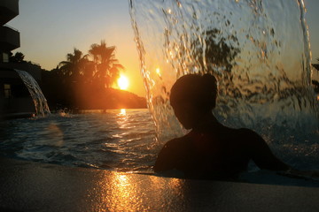 girl in the pool under the waterfall sunset