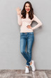© Drobot Dean - Full-length image of gorgeous female in jeans smiling and gesturing on camera with OK symbol expressing good choice over gray background