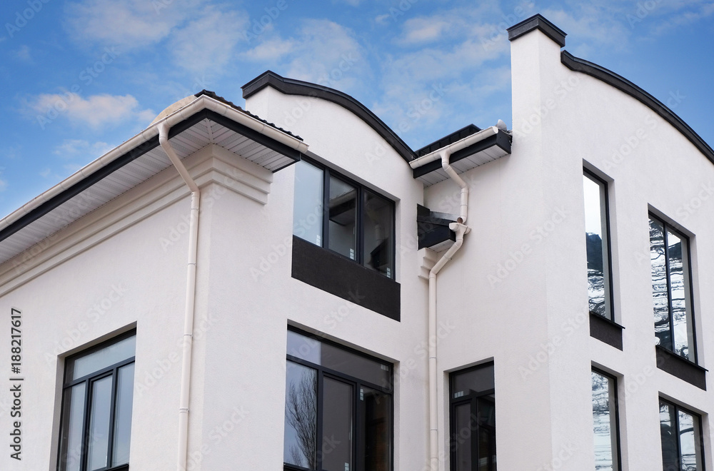Construction of a new modern house.Newly installed rain gutter on house rooftop. Frame house Rain gutter system. White gutter on the roof top of house.