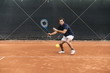 © Arno Images - Young man playing tennis on a clay court