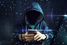 An Anonymous Hacker Without A Face Uses A Mobile Phone To Hack The System. The Concept Of Cyber Crime