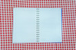 © stsvirkun - empty notebook on red and white checkered tablecloth
