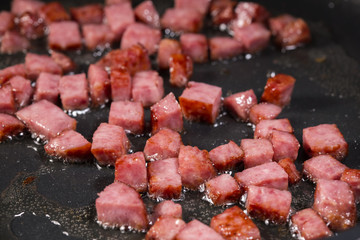 Wall Mural - Frying squares of salami in pan with cooking sunflower oil