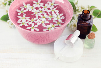 Aromatherapy beauty care set. Pink bowl with fresh flowers soak, essential oils dropper bottles.