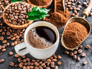 Roasted coffee beans, ground coffee and cup of coffee on wooden table.