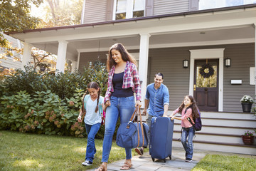 Family With Luggage Leaving House For Vacation