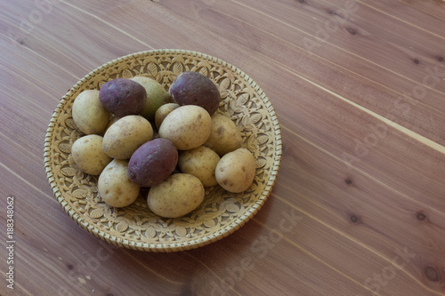 Fotografering Small red and white potatoes in a decorative birch bark bowl on a wood table, co