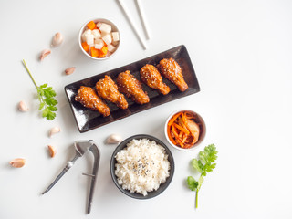 Wall Mural - Deep fried chicken wing plate with garlic sauce in Korean style serve with rice, kimchi and pickled radish on white background in top view with copy space  for asian food concept.