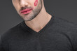 © LIGHTFIELD STUDIOS - cropped view of man with kiss print on cheek, isolated on grey