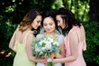 Bride and her pretty bridesmaids in pink and yellow dresses pose in the bright park