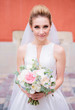 Beautiful bride poses with wedding bouquet on the streets of an old city