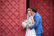 Gorgeous newlyweds kiss each other tender standing before red gates