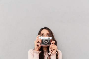 Sticker - Portrait of joyful female photographer having fun while taking photos using retro camera over gray background copy space