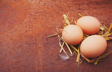 Homemade Eggs In A Straw On An Old Background.