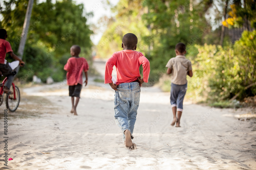 Kids running on beach sand. Children running to play in Stone Town, Zanzibar Island, Tanzania. Zanzibar daily life. - obrazy, fototapety, plakaty 