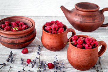 raspberry in pottery cup with lavander and pot on wooden backgro